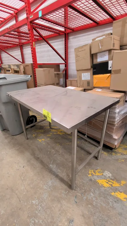2015 Winholt DTR-3048 stainless steel prep table. Features a flat top and open base with 3-sided tubular cross bracing. 4' x 2.5'. Mounted on stainles