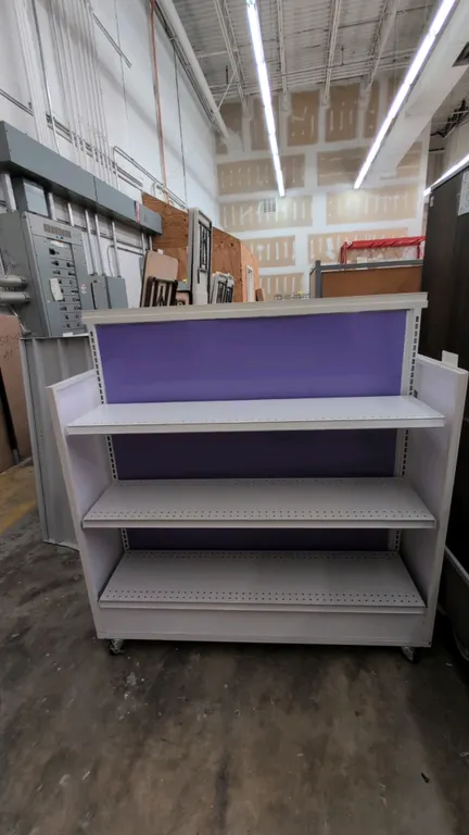 51"L portable double-sided metal merchandise display rack. Features purple back panels, adjustable perforated metal shelves, and finished end panels.