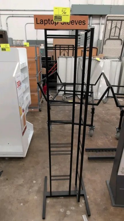 Metal merchandise display rack. Features multi-tier wire display slots and woodgrain-style "Laptop Sleeves" top header sign. 65"H. Mounted on a freest