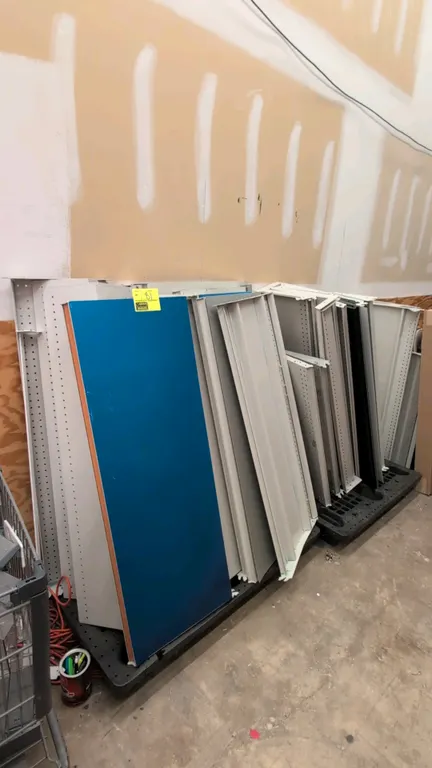Assorted retail shelving components and display accessories. Includes metal shelf panels, peg hooks, brackets, wire dividers, and related display hard