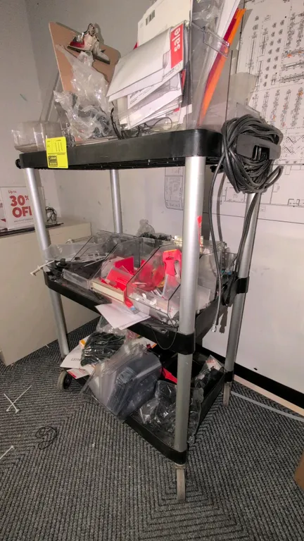 Poly 3-tier utility cart. Features black molded plastic shelves, aluminum uprights, and an integrated push handle. 30". Mounted on casters. Contents n
