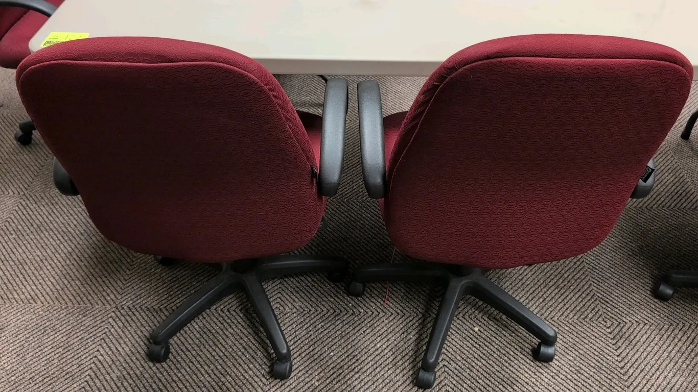Corporate Express cushioned office chairs. Features patterned burgundy cloth fabric upholstery, padded seat and backrest, and fixed armrests. Equipped