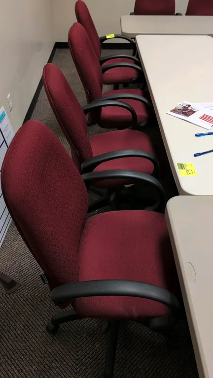 Corporate Express office chair. Features burgundy cloth cushioned seat and backrest, integrated armrests, and pneumatic height adjustment. Mounted on