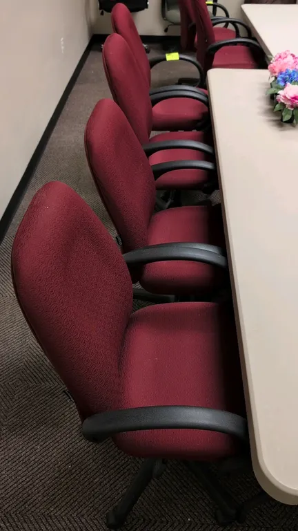 Corporate Express office chairs. Features burgundy patterned fabric upholstery with cushioned seat and back, fixed black armrests, and pneumatic heigh