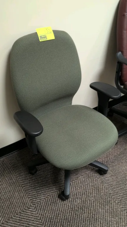 Cloth cushioned office chair. Features green patterned fabric upholstered seat and back, armrests, and pneumatic height adjustment with tilt lock. Mou