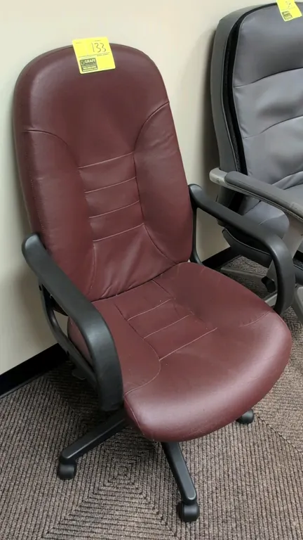 Cushioned faux leather office chair. Features burgundy faux leather upholstery, fixed armrests, and pneumatic height adjustment. Mounted on a 5-star p