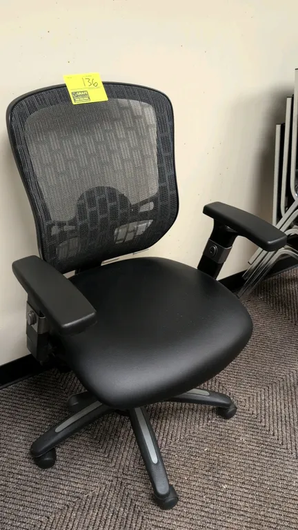 Office chair. Features a black faux leather cushioned seat, mesh back with adjustable lumbar support, and adjustable armrests. Equipped with pneumatic