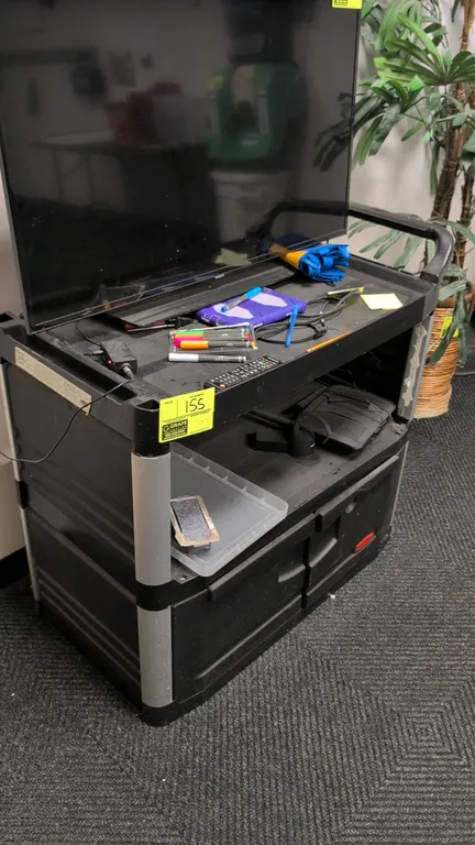 Rubbermaid 3-tier poly utility cart with lower cabinet. Features integrated push handle, open middle shelf, and enclosed bottom storage compartment wi