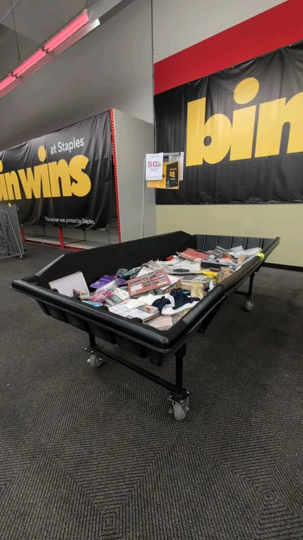 Poly dump merchandise display table. Features a black molded poly bin. 105" x 50". Mounted on a black metal tubular base with swivel casters. Contents