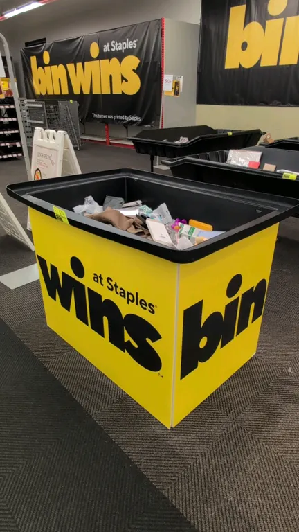 Poly merchandise dump bin rack. Features a black plastic dump tub with yellow exterior panels. 54"W. Contents not included.
