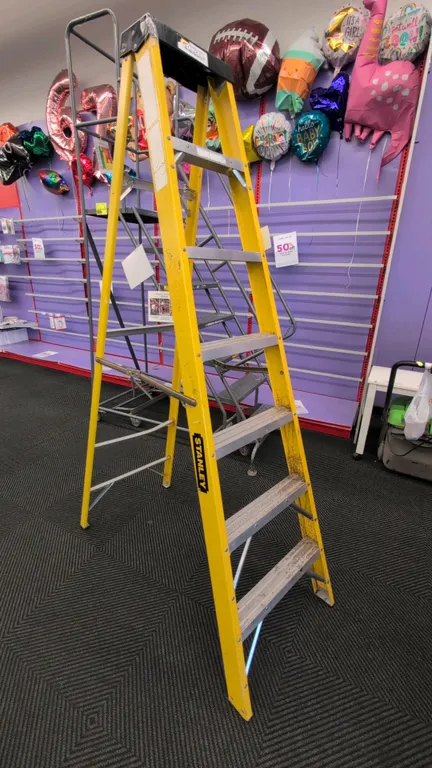 Stanley 6' fiberglass step ladder. Features non-conductive yellow fiberglass side rails, slip-resistant aluminum steps, and a molded top cap with tool