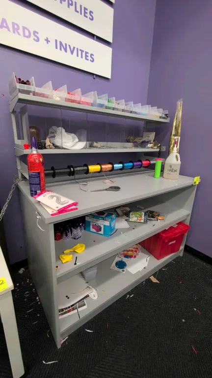Laminate storage workstation. Features open lower shelving, 2-tier metal upper shelf riser with dividers, and integrated ribbon spool rod. 5'L. Conten
