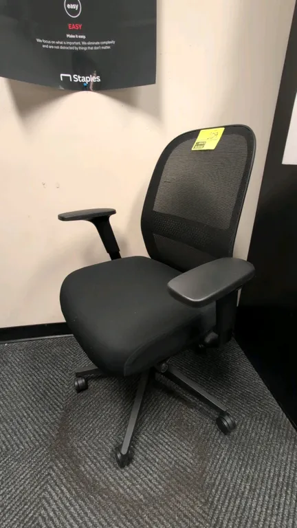 Mesh back office chair. Features black upholstered cushioned seat, breathable mesh backrest, and adjustable armrests. Mounted on a 5-star caster base.