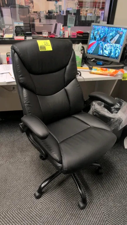 Faux leather cushioned office chair. Features black faux leather upholstery, padded armrests, and a 5-star base with casters.