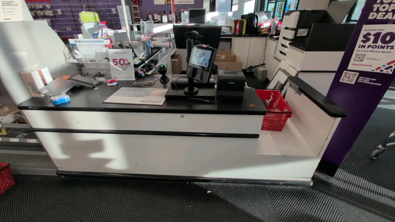 4-sided laminate service counter. Features under-counter storage cabinets, open shelving, black countertops with bumper trim, and overhead pole-mounte