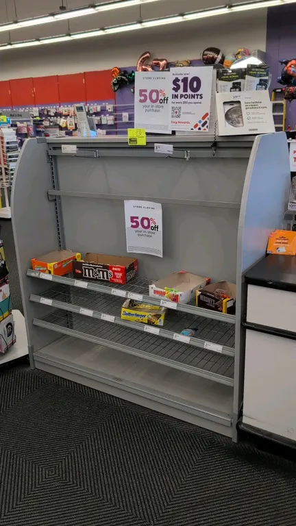 Laminate merchandise display rack. Features gray laminate construction with curved side panels, adjustable wire shelves with integrated price tag chan