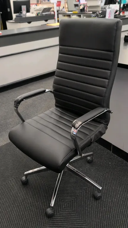 2019 Bentura 53234 high-back faux leather office chair. Features black ribbed upholstery, fixed armrests, and chrome frame. Mounted on a 5-star chrome