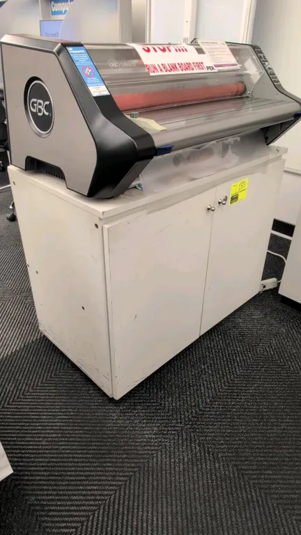Laminate portable cabinet. Features white laminate construction, 2 hinged doors, 1 interior shelf, and door lock mechanism. 3'W. Laminator on top and