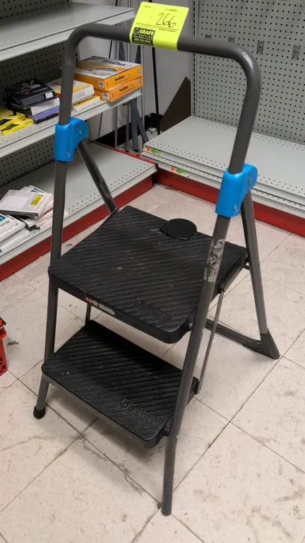 Cosco 2-step folding ladder. Features a folding tubular steel frame, large slip-resistant textured steps, top handrail, and non-marring feet.