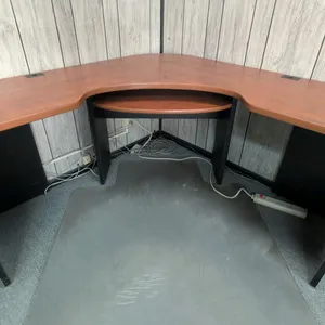 Laminate wood L-shaped corner desk. Features a pull-out keyboard tray, cherry-tone top finish, black panel base, and integrated wire grommets. 61" x 6