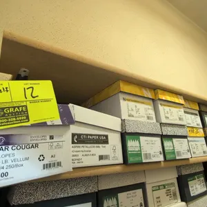 Assorted specialty envelopes and announcement cards on shelf. Includes various brands such as Domtar, Neenah Paper, Wausau, and Leader. Features assor