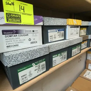Assorted A6 envelopes on shelf. Includes boxes from Domtar, Neenah Paper, and Wausau Paper in various colors, finishes, and paper weights. Standard A6