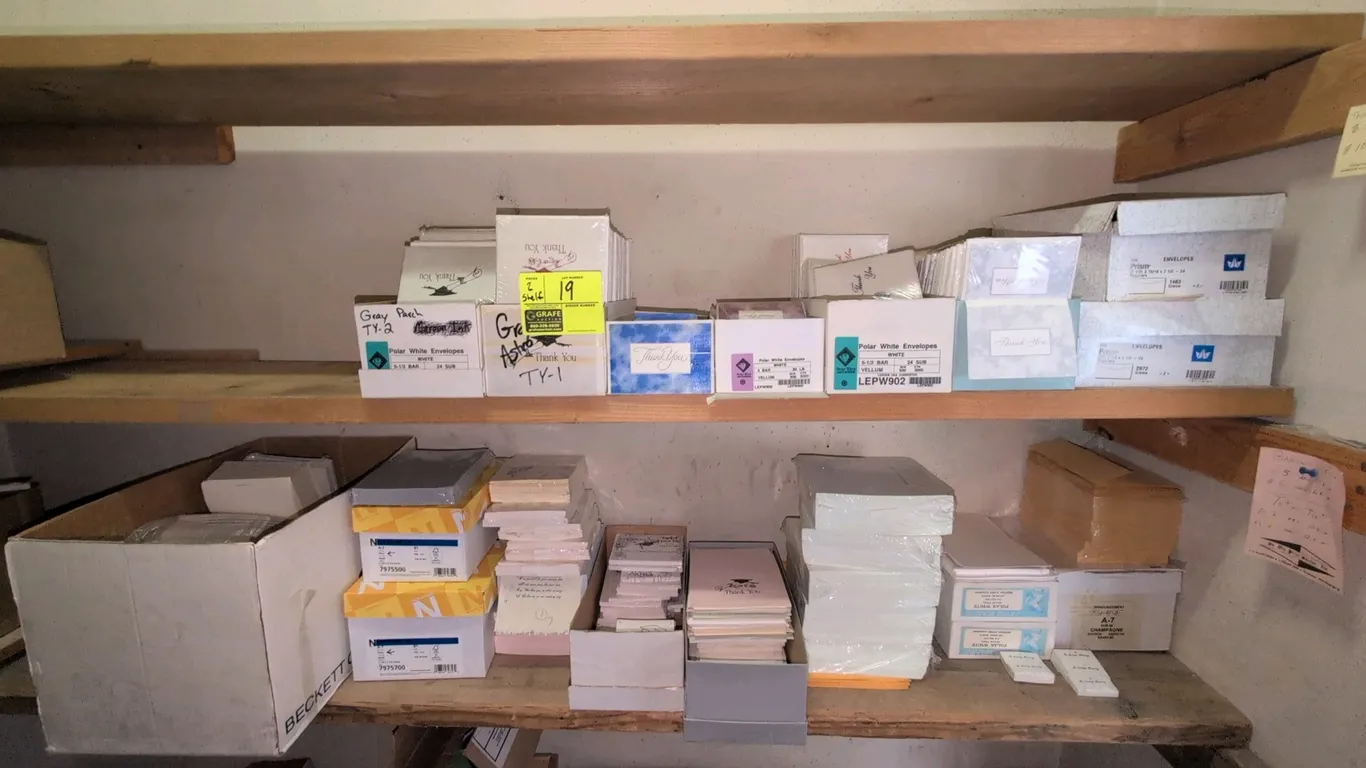 Assorted stationery and paper products lot. Includes envelopes, thank you notes, graduation invitations, and specialty paper across (2) shelves. Featu