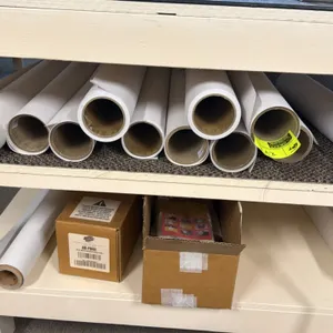 Assorted plotter paper rolls compatible with HP DesignJet Z6 Pro production printers. Includes loose rolls and boxed media. Shelving unit and surround