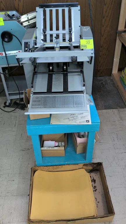Baumfolder 714XE Ultrafold friction feed tabletop paper folding machine. Features adjustable fold plates, friction feed table, and delivery tray. Incl