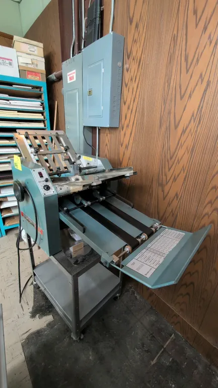 Baumfolder 714 tabletop paper folding machine. Features 14 x 20 series format, adjustable fold plates, dial controls, and discharge conveyor. Includes