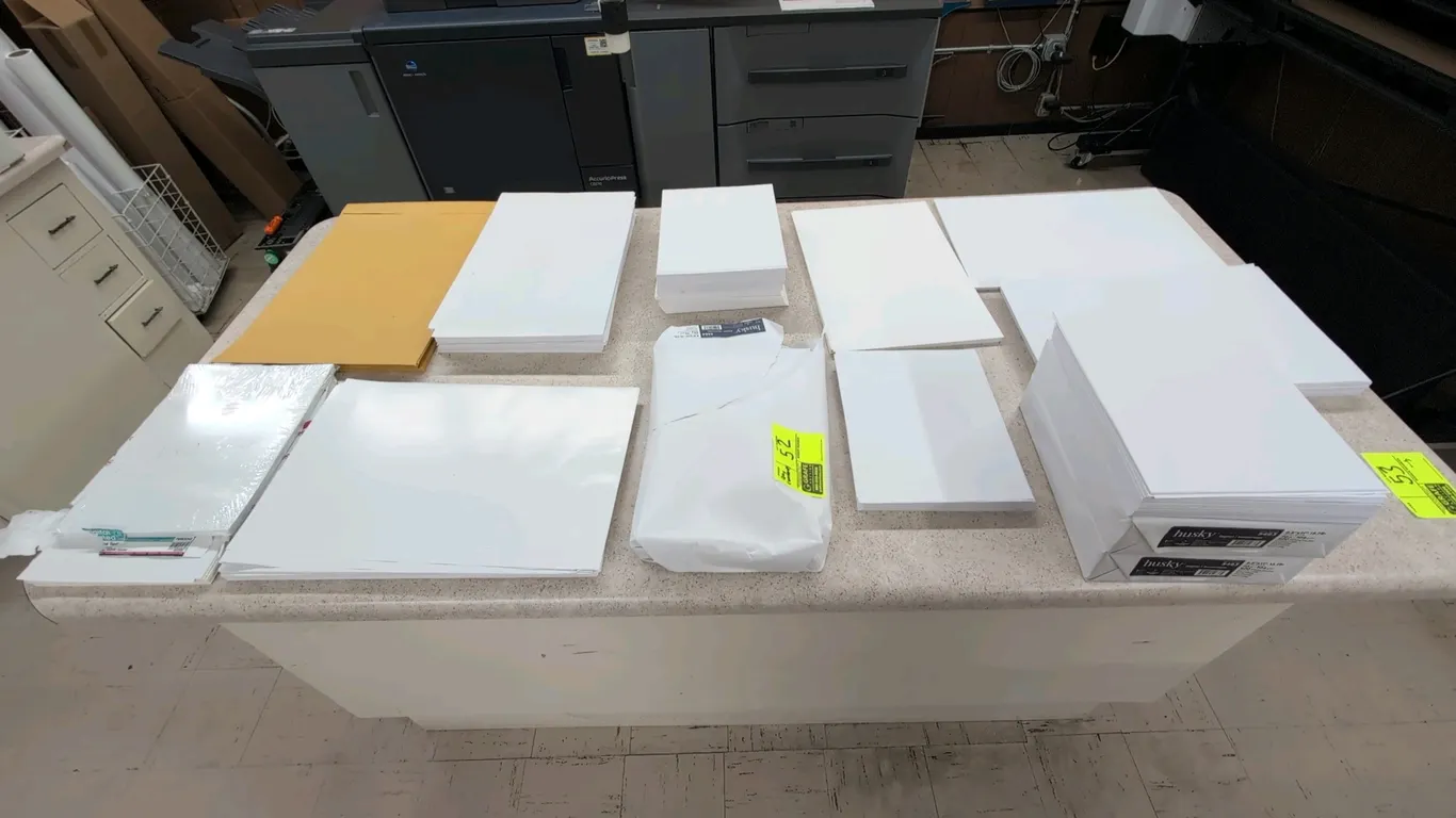 Assorted paper products and office stock. Includes Domtar Husky Digital 8.5" x 11" 70 lb paper, Nekoosa coated gloss text paper, large kraft envelopes