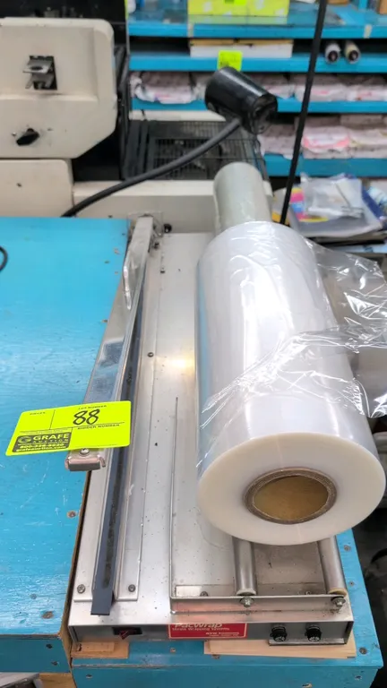 ATW PacWrap PW 16/27 shrink wrapping system. Features stainless steel housing, film roll cradle rollers, and sealing bar. S/N: 12024. Electrical: 120V