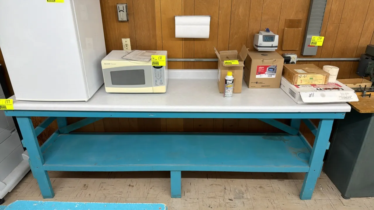 Wooden work table. Features a laminate top with integrated backsplash, painted blue wooden frame, and full-length undershelf. Dimensions: 8'L x 2'W x