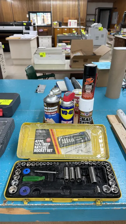Assorted tool set and maintenance chemicals. Includes a 1/4" and 3/8" drive socket set in a yellow metal case, WD-40, Tri-Flow lubricant, JB heavy-dut