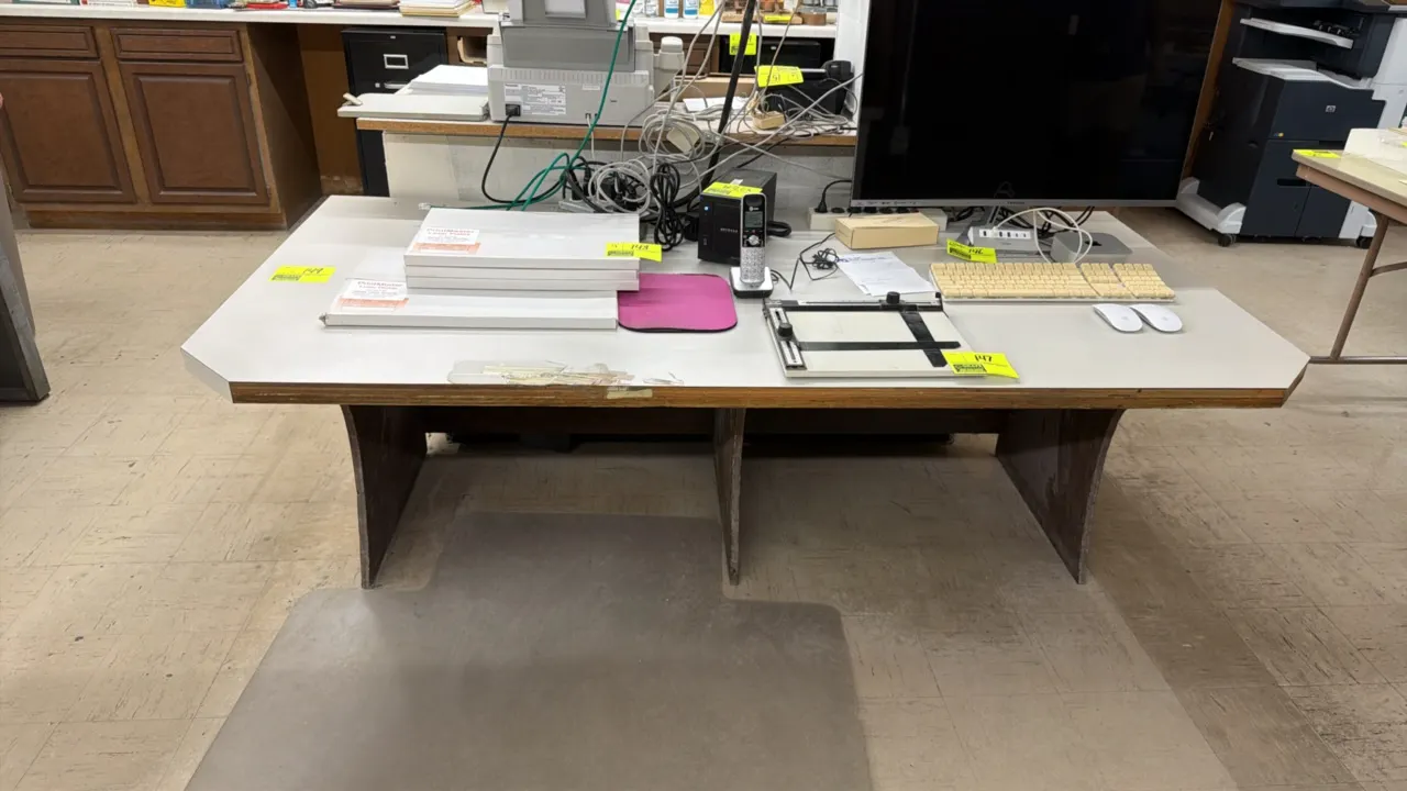 Laminate office desk. Features a light gray laminate work surface with wood edge trim and panel leg base. Dimensions: 6'L x 3'W x 2.5'H. Contents not