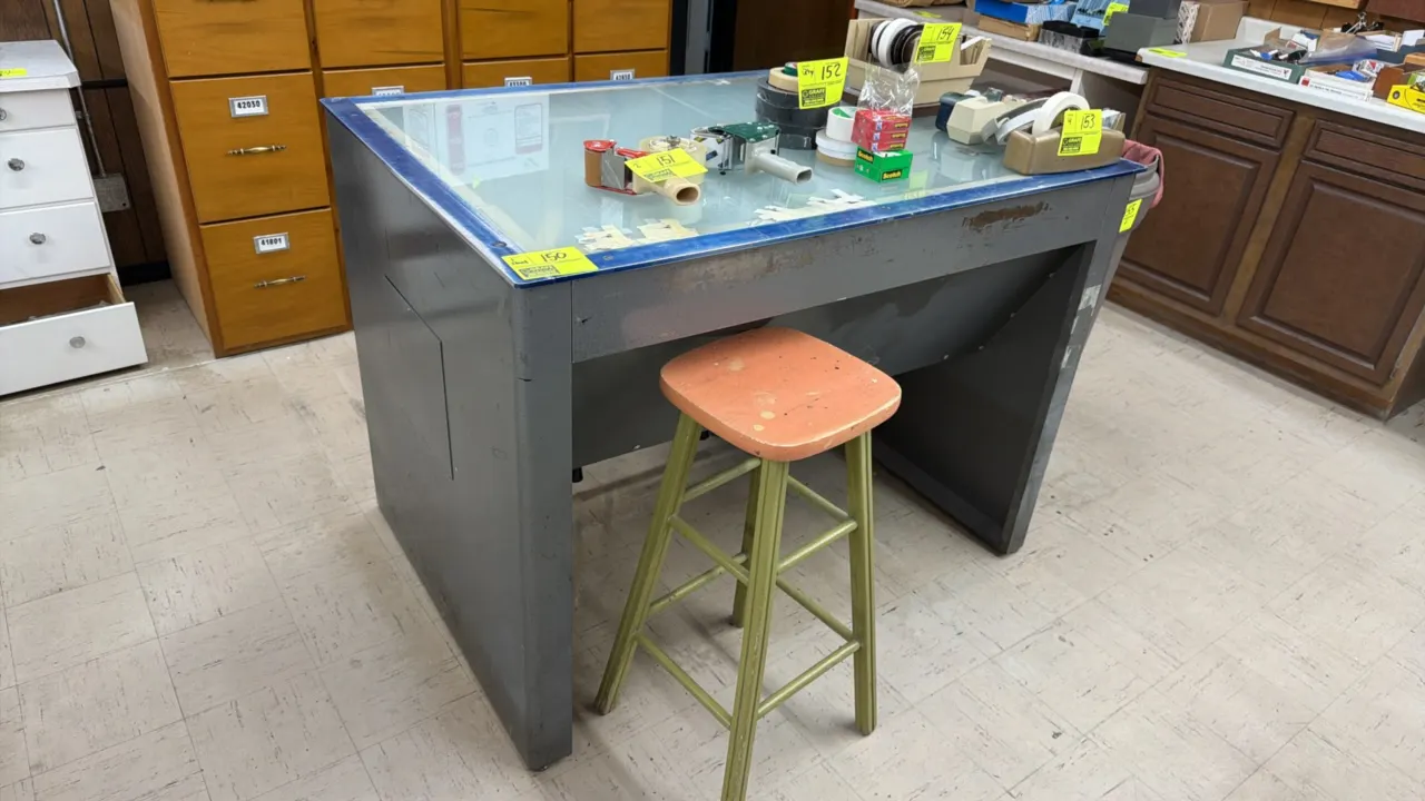 Vintage metal graphic arts light table with (2) assorted stools. Features an illuminated glass work surface and heavy-gauge steel construction. 3' x 4