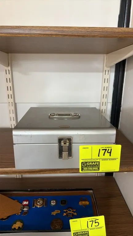 Metal lockable cash box. Features hinged lid with top folding carry handle, multi-compartment interior tray, and front latch. Key included.