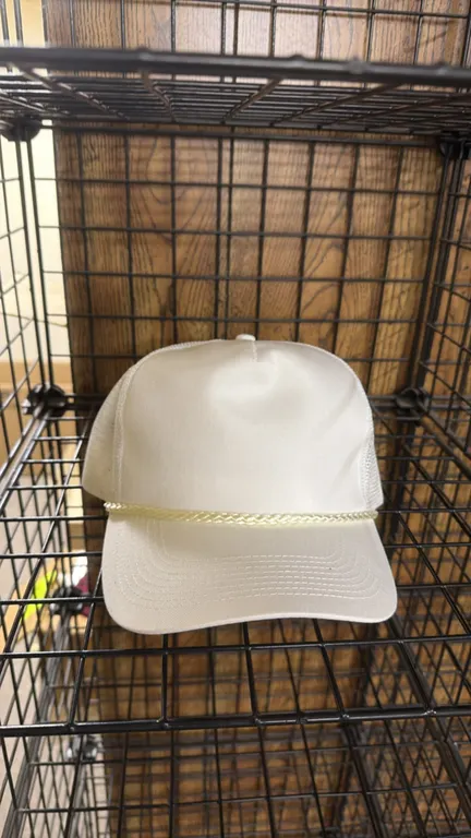 Blank snapback trucker caps. Includes (6) white caps featuring solid front crown with braided rope trim, breathable mesh back panels, and adjustable p