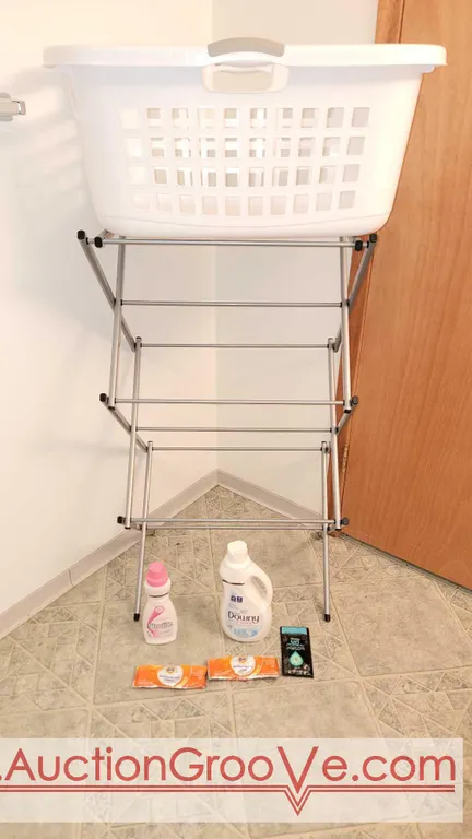 A collapsible metal clothes rack, a LAUNDRY basket, Woolite & Downy detergents, a couple of Tide washing machine cleaner packs and an Un-Stopables