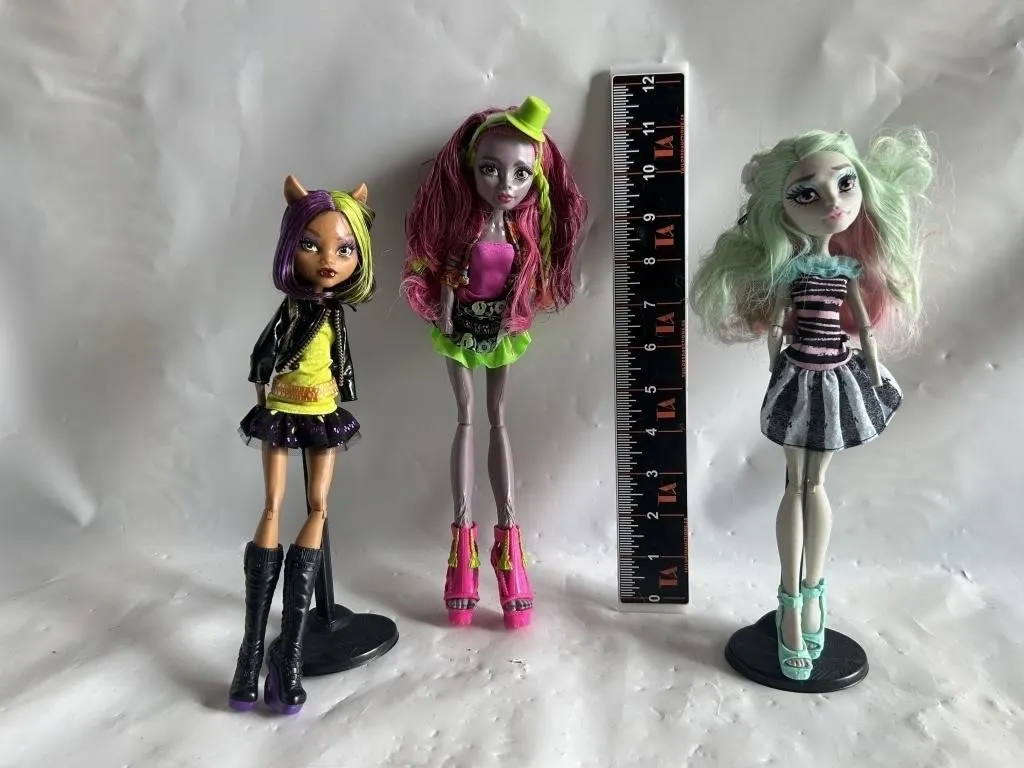 Three Monster High fashion dolls with stands