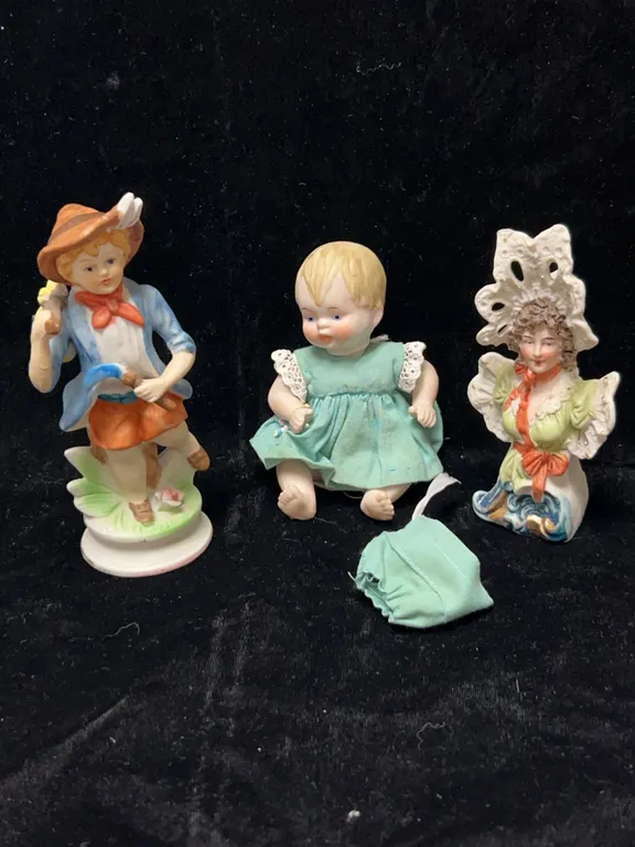 3 Porcelain Figurines: Boy with Satchel, Seated Baby in Dress, and Woman in Bonnet Bust 4-5" High
