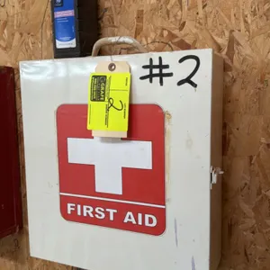 Wall-mount metal first aid cabinet. Features white painted finish, First Aid cross front decal, top carrying handle, side latch closure, and three int