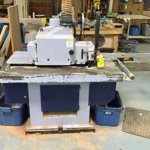 Straight-line rip saw. Features overhead feed mechanism, adjustable rip fence, top dust collection port, and control panel with push-button controls, 
