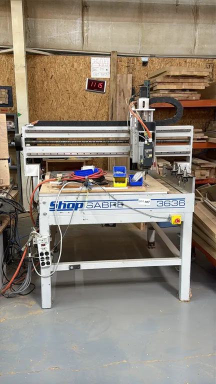 Shop Sabre 3636 3-axis CNC router table. Features 3' x 3' working area, HSD spindle, linear tool holder rack with tool holders, and cable carrier trac