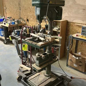 Central Machinery T-149 9-speed drill press. Features adjustable work table, drill chuck, and mobile wheeled base. Includes Kurt D675 6" precision mac