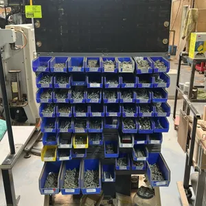 Double-sided mobile parts bin rack. Features louvered hanging panels, assorted plastic storage bins, lower 4-drawer small parts cabinet, and contents 
