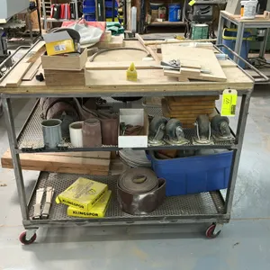 3-tier metal cart with wood top. Features steel frame construction, wire mesh lower shelves, and dual push handles. Includes contents shown such as sa