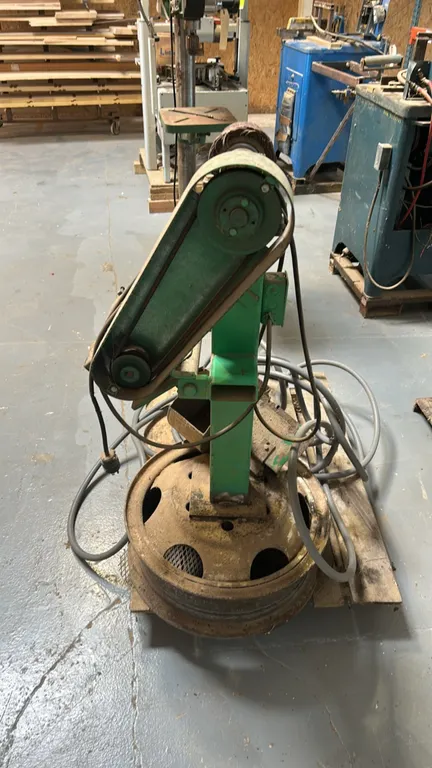 Burr King 760 three-wheel belt grinder. Features abrasive flap wheel attachment and electric drive motor. Mounted on pedestal stand with rim base. Not