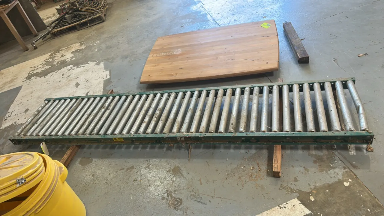 Gravity roller conveyor track section. Features green metal channel frame with steel rollers. 10'L x 2'W. Note: End roller is bent.