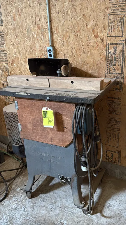 Davis & Wells wood shaper. Features cast iron base, wood fence, dust collection hood, side-mounted motor with wire mesh guard, wood enclosure, and Squ
